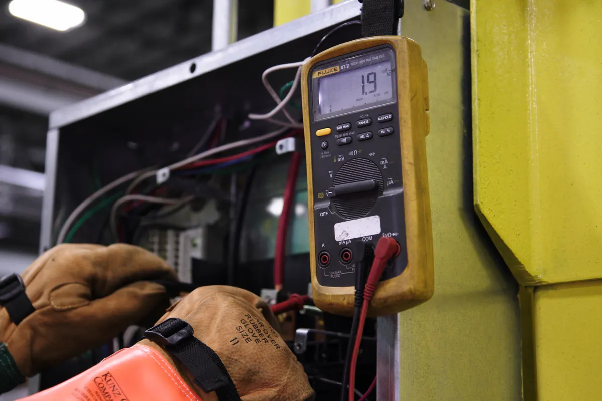 Technician testing electrical panel with a multimeter during apartment inspection