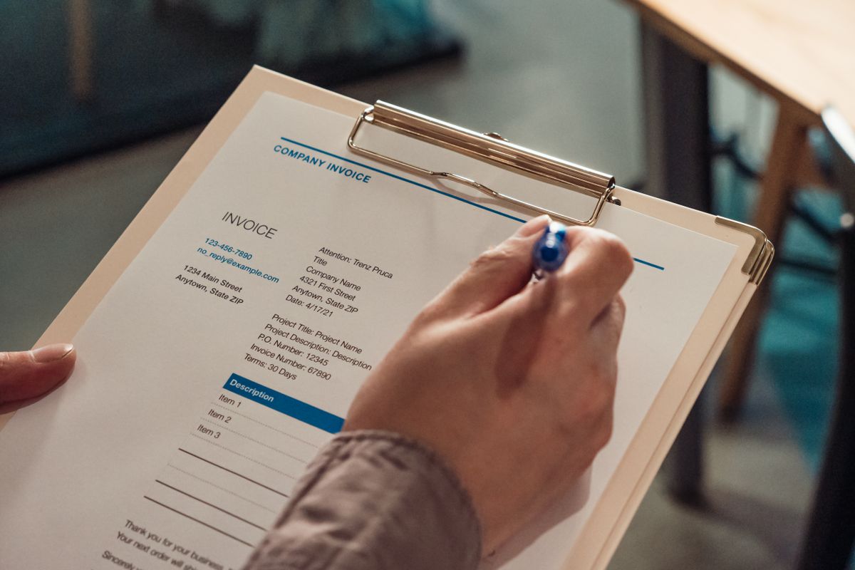 A person reviewing and filling out a detailed cost estimate invoice on a clipboard