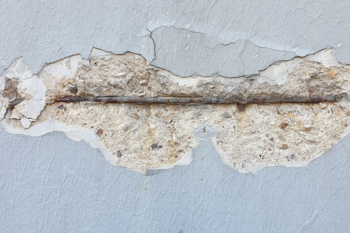 Exposed rusted rebar in cracked concrete structure illustrating the need for technical inspection.