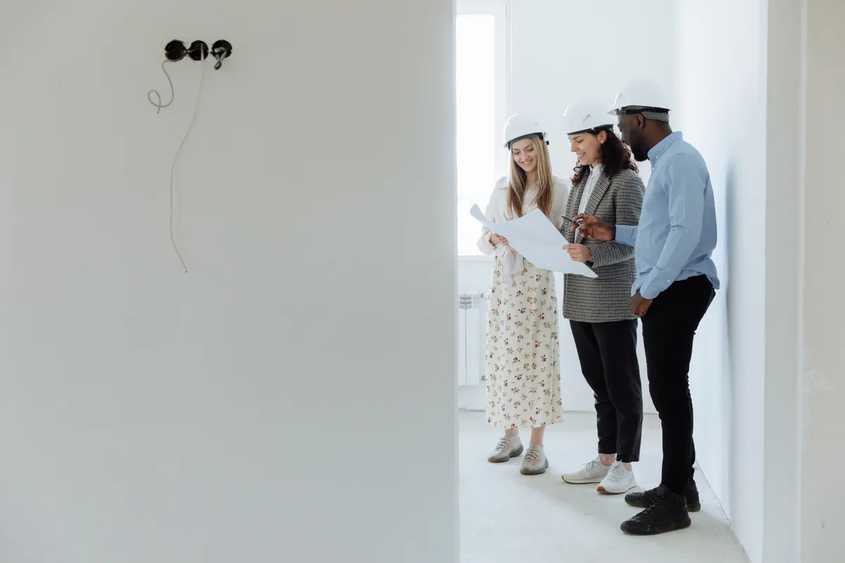 Architects and clients reviewing construction blueprints on site during the project planning stage.
